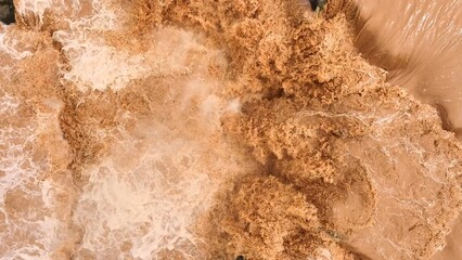 Overhead perspective reveals turbulent muddy waters flowing forcefully, demonstrating how...
