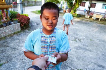 Asian boy receives money from parents before going to school