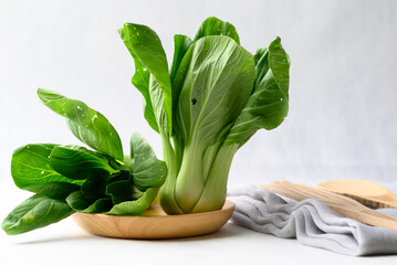 Organic Bok choy or Pak choi on wooden plate with white background, Fresh vegetable, Food ingredient