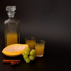 Fruit liqueur made from green grapes and mango with cinnamon and anise on a black background.
