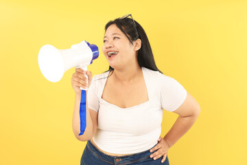 The Chubby Asian Woman Standing on the Yellow Background with the White T-Shirt Holding Megaphone