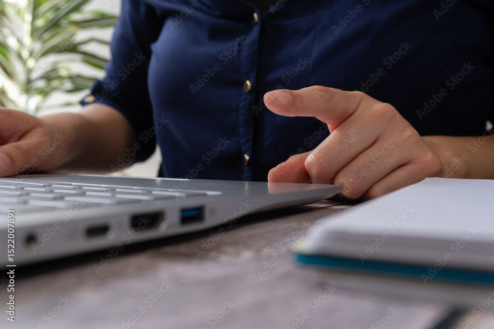 Poster a close-up of hands typing on the keyboard, with an open notebook beside it and a laptop in front of