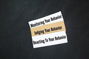 Box paper with the words monitoring your behavior, judging your behavior and reacting to your...