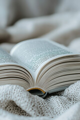 Open book resting on soft, textured blanket, inviting readers to explore its pages. warm tones create cozy atmosphere, perfect for reading