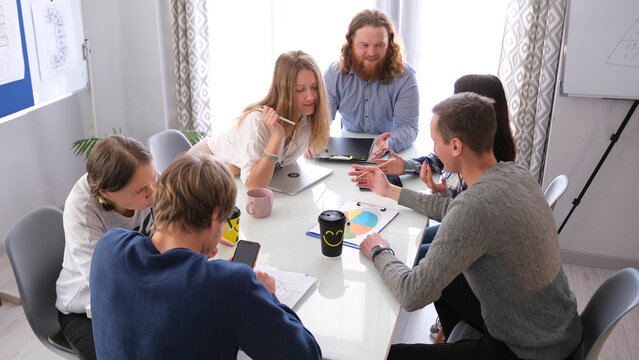 A group of people are sitting at a table and working on a project together. An atmosphere of cooperation and concentration