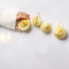New Year decorative ornaments in female hand, golden Christmas flashlights bauble on white fur with...