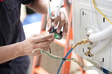 Man Using Electrical Tape on Wires During AC Installation, Technician Repairing Air Conditioner Wiring, HVAC Professional Working on Electrical Connections