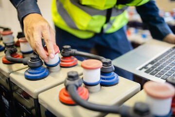 Technician performs maintenance on backup power system battery ensuring reliable energy supply and...