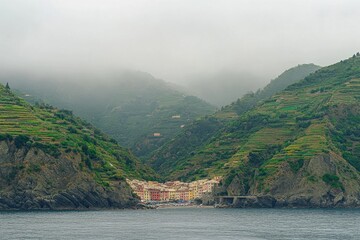 Manarola village nestled between green hills and misty mountains along the coast of Italy, The seaside village of Manarola sits on the famous cliffs of Cinque Terre in La Spezia, Italy
