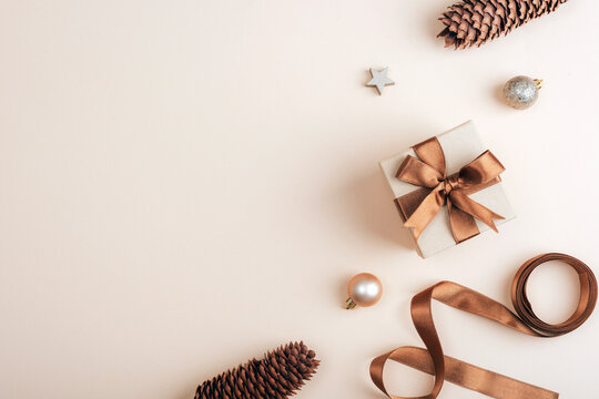 Flat lay with gift box, pine cones and christmas ornaments on soft beige background. Top view, copy space