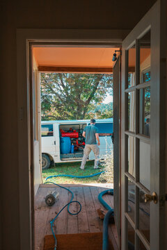 Carpet cleaning professional outside home with hoses running to van