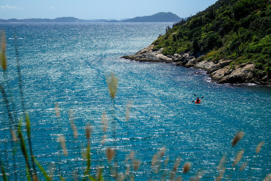 Passeio de caiaque no litoral rochoso e no mar azul claro e brilhante.