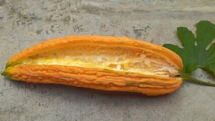 The perfectly ripe bitter melon is placed on the cement floor. The bitter melon is peeled.