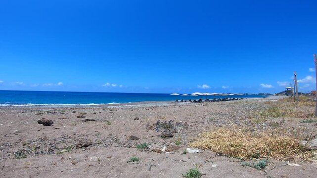 Beach beds lined up on the quiet coast of Mandria Beach, Cyprus. Peaceful setting with calm sea and blue sky&mdash;ideal for travel, summer holiday, relaxation, and Mediterranean lifestyle footage.