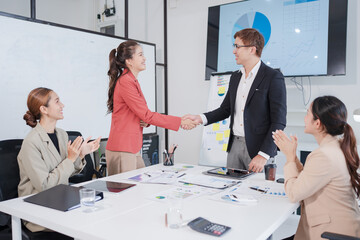 Asian businesspeople show their congratulations, shake hands, and the team applauds.