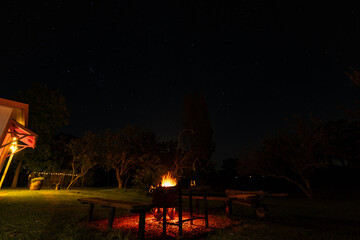 Fire pit burning brightly in rural Australian backyard at night under star lit sky
