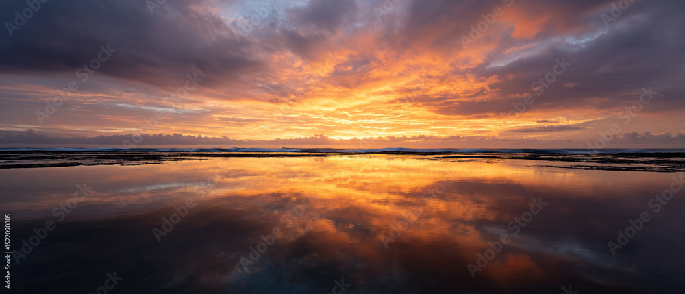 Aufkleber golden hour sky with clouds reflected on calm water, warm tones create peaceful and serene atmospher