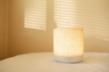 Essential oil diffuser in minimalist space with filtered sunlight illuminating wall