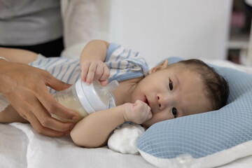 A woman is caring for her newborn baby, holding and breastfeeding her. She lays the baby gently on the bed. This image represents care and attention.

