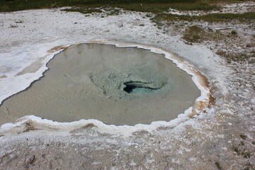 Vibrant hot spring in a national park with clear blue water and surrounding mineral deposits in daytime