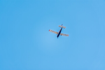Small ultralight airplane with overhead wing and single propeller flying in sunset sky.