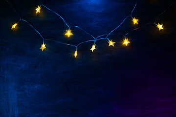  glowing garlands.Christmas wallpaper With Yellow stars on a blue background.space for text.Star...