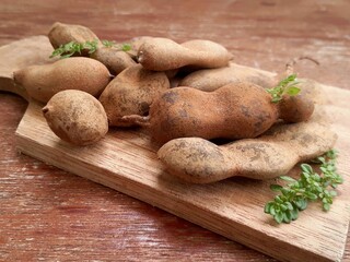 A collection of fresh tamarind or Tamarindus indica or Asam Jawa and leaf on a wooden table.