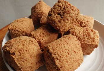 Brown raw tofu in cube shape on a plate ready to be cooked. Indonesian tofu is called Pong tofu.