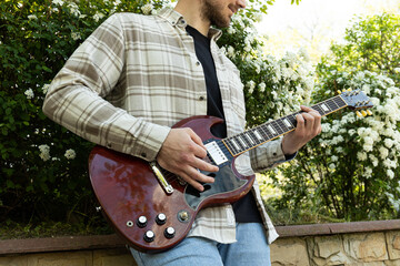 Attractive young guy playing guitar in the park
