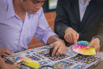 Team graphic designer checking print quality of media graphics proof print and color guides in...