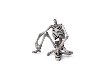 Haunted by ghosts. headless skeleton sits near his skull with a ghostly face  isolated on white background.