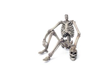 Haunted by ghosts. headless skeleton sits near his skull with a ghostly face  isolated on white background.