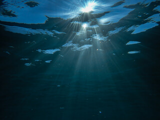 Naklejka premium Ocean blue underwater with sunrays, Underwater Sea Deep Water Abstract Sunshine, sea wave , clean waters in summer time, Natural underwater seascape, sand on ocean floor and water surface with sunligh