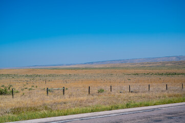 Vast open landscape showcasing rolling hills and a clear blue sky in a rural area during the midday...