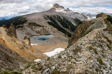 Mountain landscape with alpine lake and rocky terrain under cloudy sky in the wilderness during summer