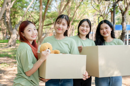 Young Women Volunteers Carrying Donation Boxes Outdoors, Group of Friends Preparing for a Charity Drive