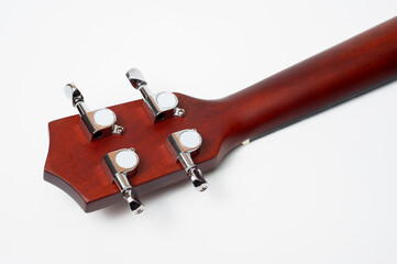 Ukulele made of natural wood of dark color photographed on a white background.