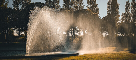 Golden sunlight sparkling through water fountain in Borely Park, Parc Borély, Marseille, Marseilles, France. Fine art summer scene of shimmering water spray