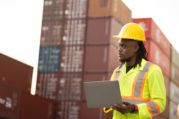 African worker working with use notebook computer checking container at container site	