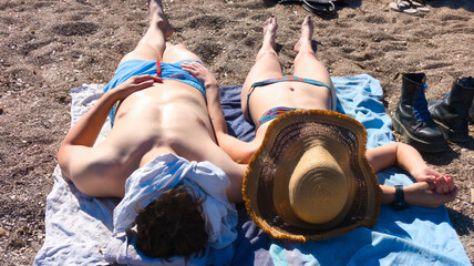 young couple sunbathing side by side on a beach towel, holding hands and relaxing in swimsuits. Plage du Prado, Marseille, Prado Beach, Marseille, France