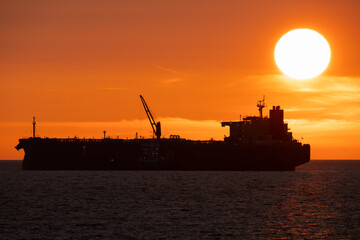 Silhouette of a huge oil tanker and a bunker vessel against a fiery sunset in the Baltic Sea off...