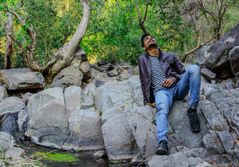 young man sitting on a rock in woods