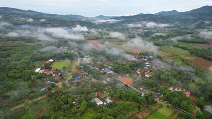 Aerial view from drone of the rural village in the mountains on foggy day