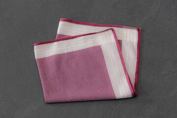 Elegant folded handkerchief with striped design, displayed on a dark stone surface. Suitable for concepts related to men’s fashion accessories, style, or fabric textures.