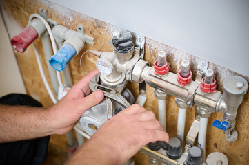 Man adjusting the heating system in a new apartment. Plumber adjusting heat on the central system...