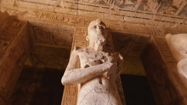 Dramatic interior view of the Abu Simbel Temple in Egypt, highlighting monumental statues of Pharaoh Ramses II and intricate hieroglyphics on the walls and ceiling.