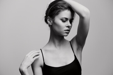 Fototapeta premium Elegant woman posing with a thoughtful expression, highlighting her graceful posture against a soft gray backdrop. Black and white art portrait showcasing beauty.