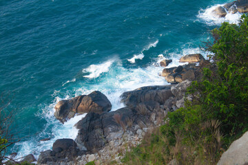 Scenic tropical coastline with steep rocky cliffs and lush green forest descending into turquoise ocean waters