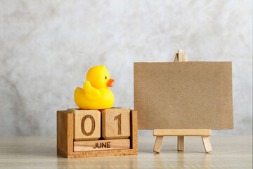 Wooden calendar showing june 1st with rubber duck and blank canvas on easel