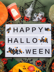 Happy Halloween greetings on lightbox on green with confetti